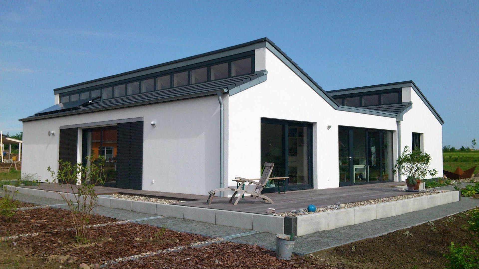 Modernes weißes Einfamilienhaus mit Pultdach großen Fensterfronten und einer Terrasse im Außenbereich